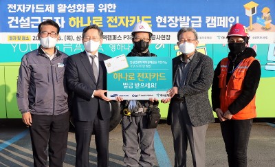 박성호 하나은행 은행장(왼쪽에서 두 번째), 삼성엔지니어링 김창용 상무(왼쪽에서 첫 번째), 건설근로자공제회 송인회 이사장(왼쪽에서 네 번째), 현장 건설근로자 대표 등이 기념 촬영을 하고 있다. 사진=하나은행.