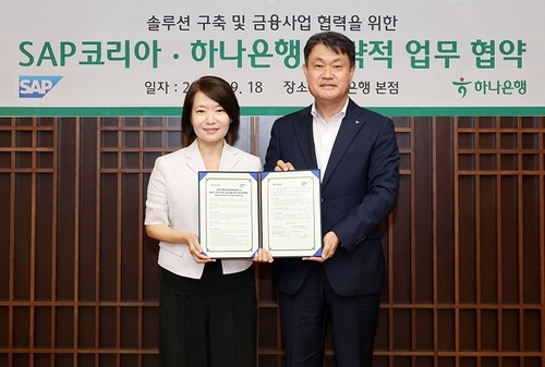 하나은행은 지난 18일 을지로 본점에서 세계적인 ERP 소프트웨어 기업 SAP코리아와 솔루션 구축 및 금융사업 협력을 위한 업무협약을 체결했다. 이날 협약식에 참석한 성영수 하나은행 기업그룹 부행장(사진 오른쪽)과 신은영 SAP코리아 대표이사(사진 왼쪽)가 협약서를 들고 기념촬영을 하고 있다. 사진=하나은행