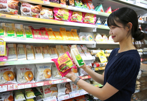 모델이 소이갈릭버거, 갈릭치킨포테이토샌드위치를 살펴보고 있다. 사진=GS리테일.